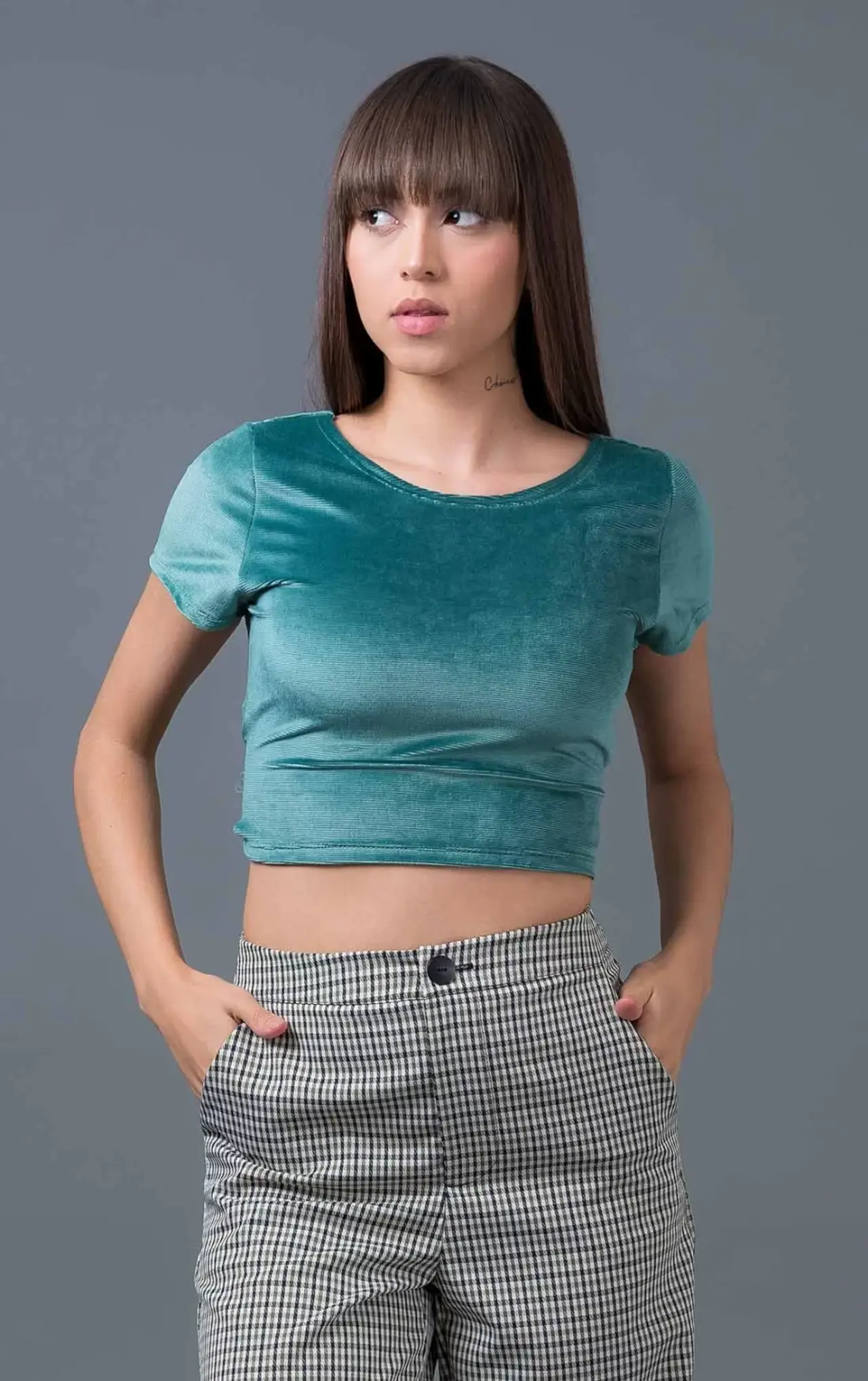 menina com um top cropped verde fazendo pose descontraída olhando para o lado